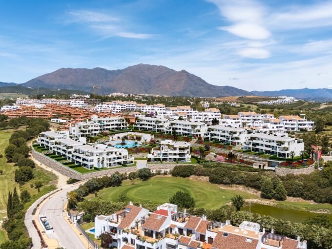 Aerial view of the apartment blocks on the golf course with the mountains behind at Amaranta Living, Casares